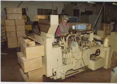 Werknemer aan machine sigarenfabriek Cogétama